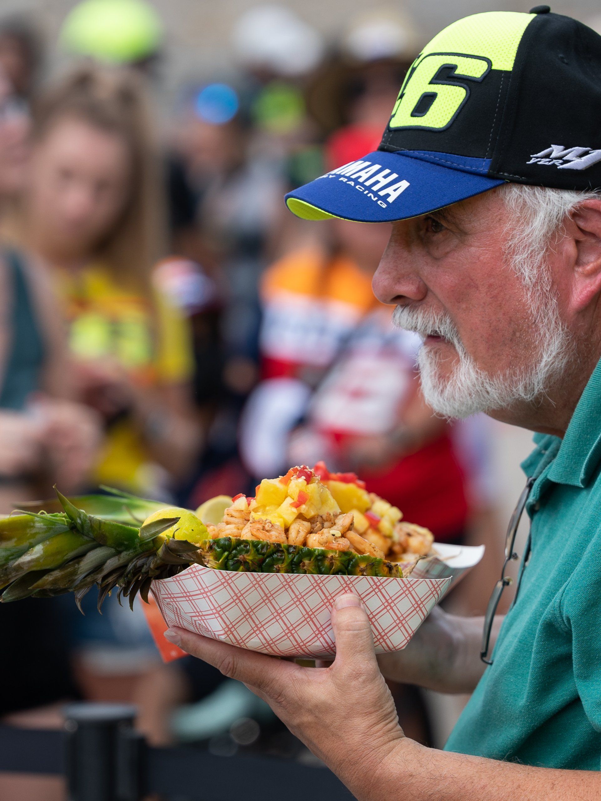 A MotoGP fan holding the carved-pineapple shrimp bowl at Circuit of the Americas