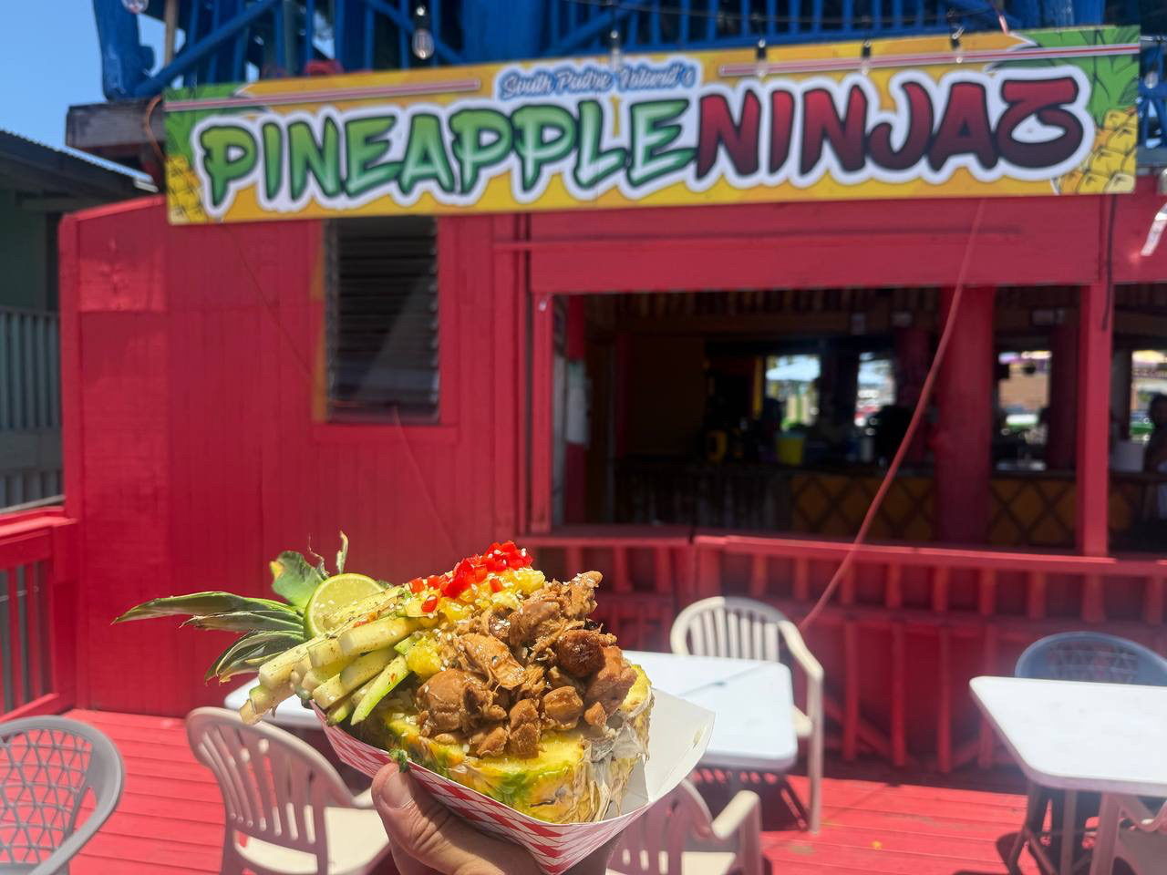 Grilled chicken Island Bowl held in front of the red Pineapple Ninjaz building on South Padre Island