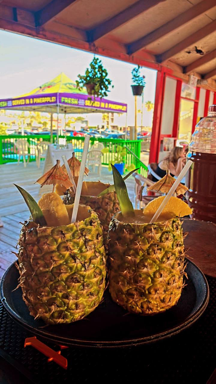 Two piña coladas served in fresh-carved pineapples at the South Padre Island waterfront bar
