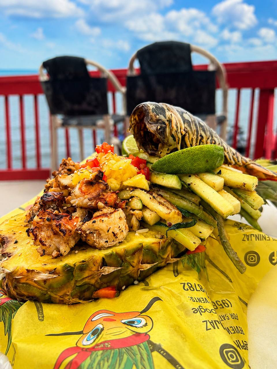 Gulf lobster and grilled shrimp piled into a fresh-carved pineapple bowl with the bay behind